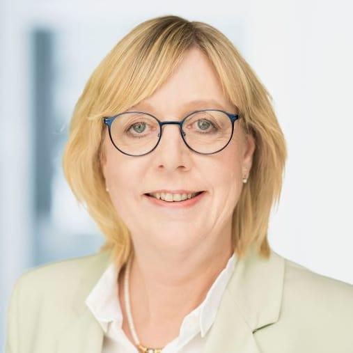 Eine Person mit kurzen blonden Haare. Sie trägt eine Brille und ein Hemd.