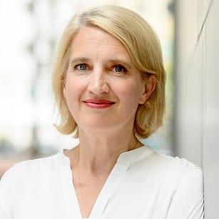 Eine Person mit kurzen blonden Haaren trägt ein weißes Hemd.