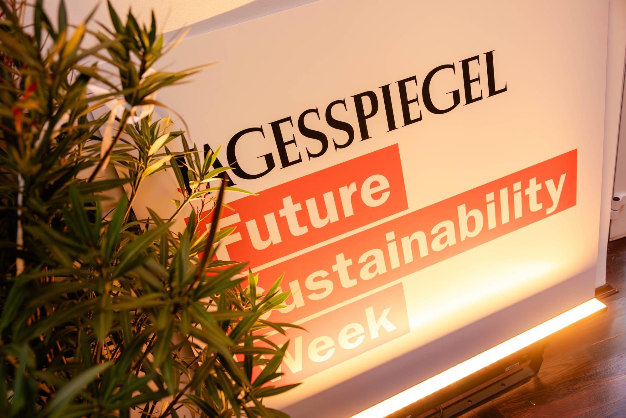 Ein Schild mit der Aufschrift ‚Tagesspiegel Future Sustainability Week‘, teilweise verdeckt von grün