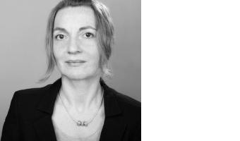 Eine Frau mit zusammengebundenen Haaren, die einen Blazer trägt.