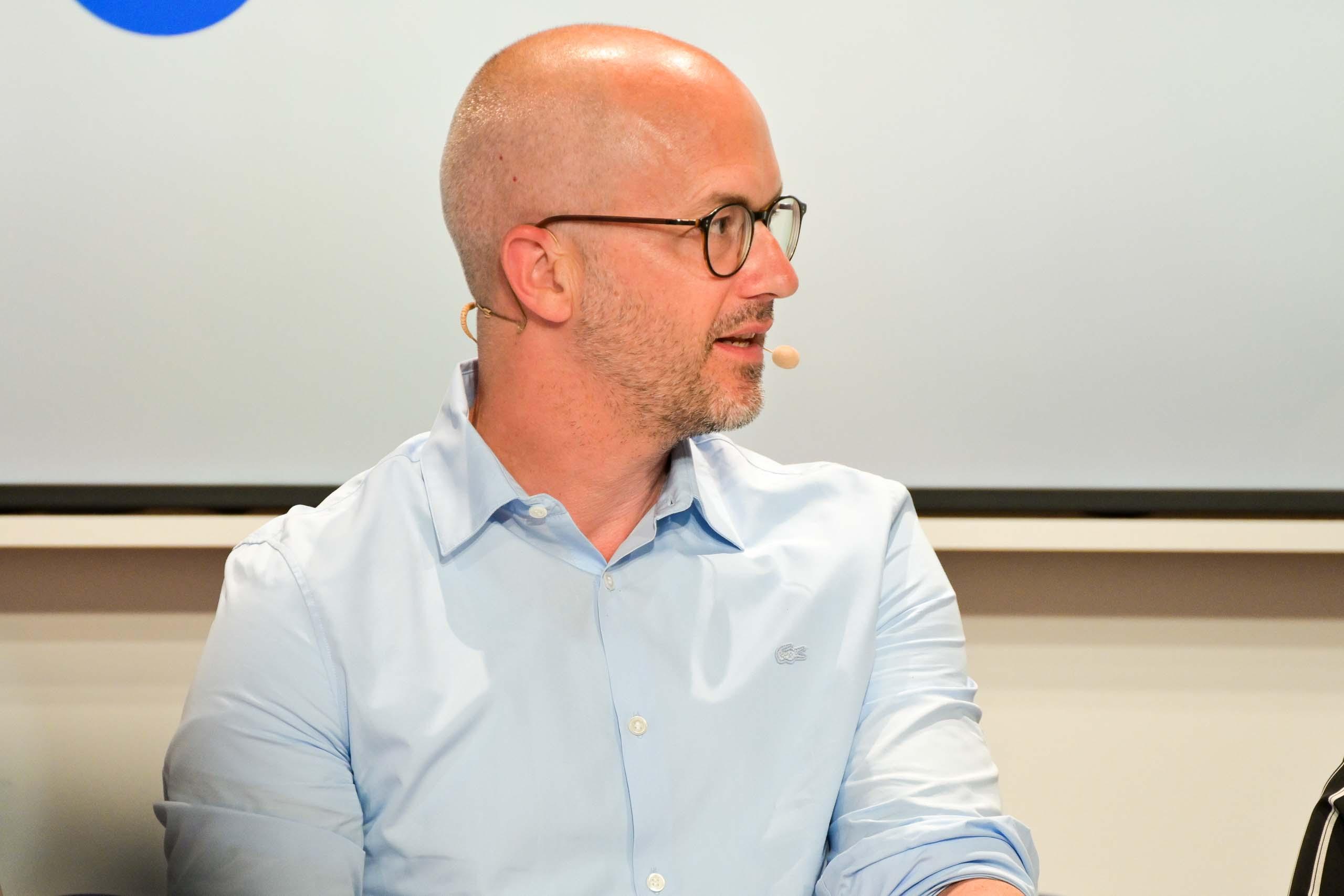 Ein Mann mit Brille, der eine hellblaues Hemd trägt.