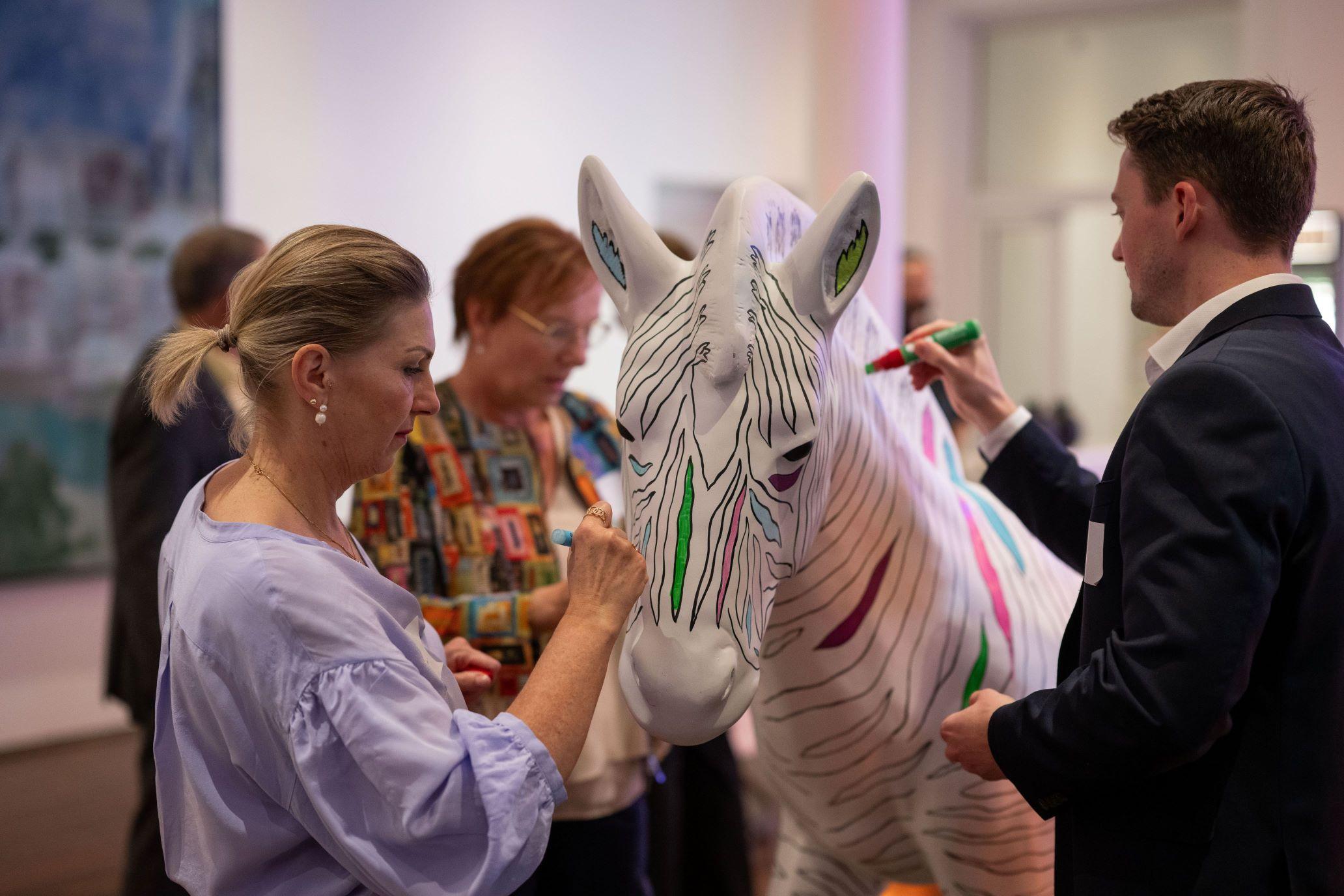 Personen malen ein weißes Zebra an.