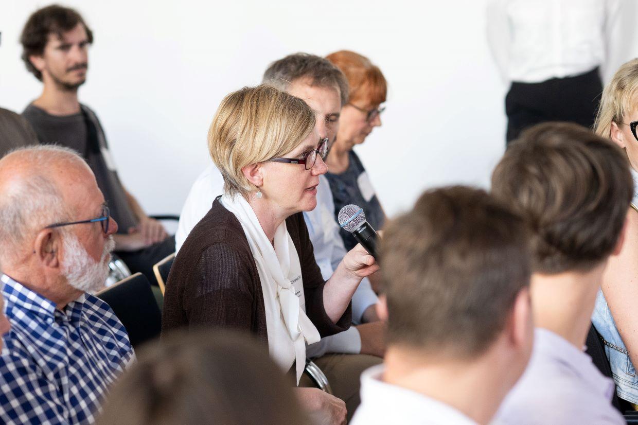 Teilnehmerin im Publikum stellt mit Mikrofon eine Frage zur digitalen Gesundheit.