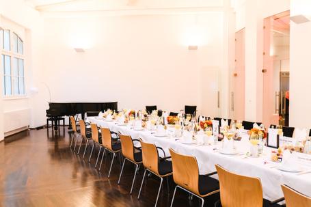 Festlich gedeckter Tisch mit Deko, Holzfußboden, großen Fenstern und Klavier.