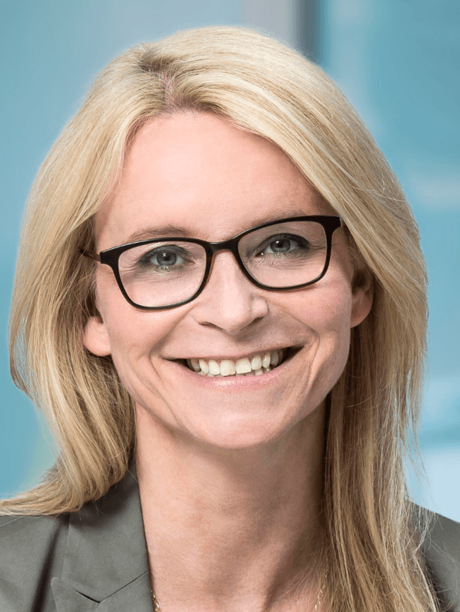 Eine Frau mit blonden langen Haaren. Sie trägt eine Brille.
