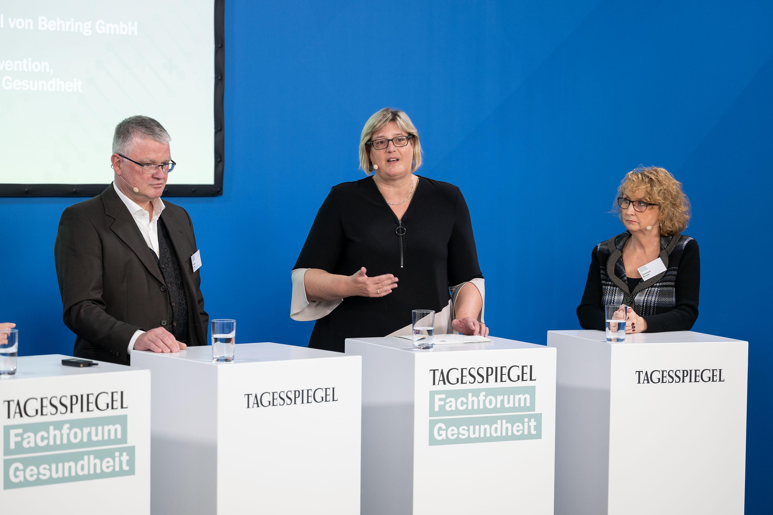 Drei Personen stehen jeweils hinter einem Rednerpult.