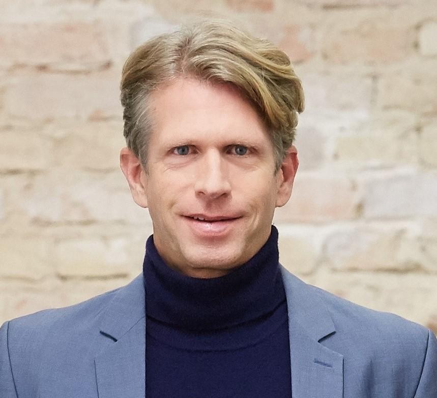 Eine Person mit hellen Haaren, in einem Anzug.