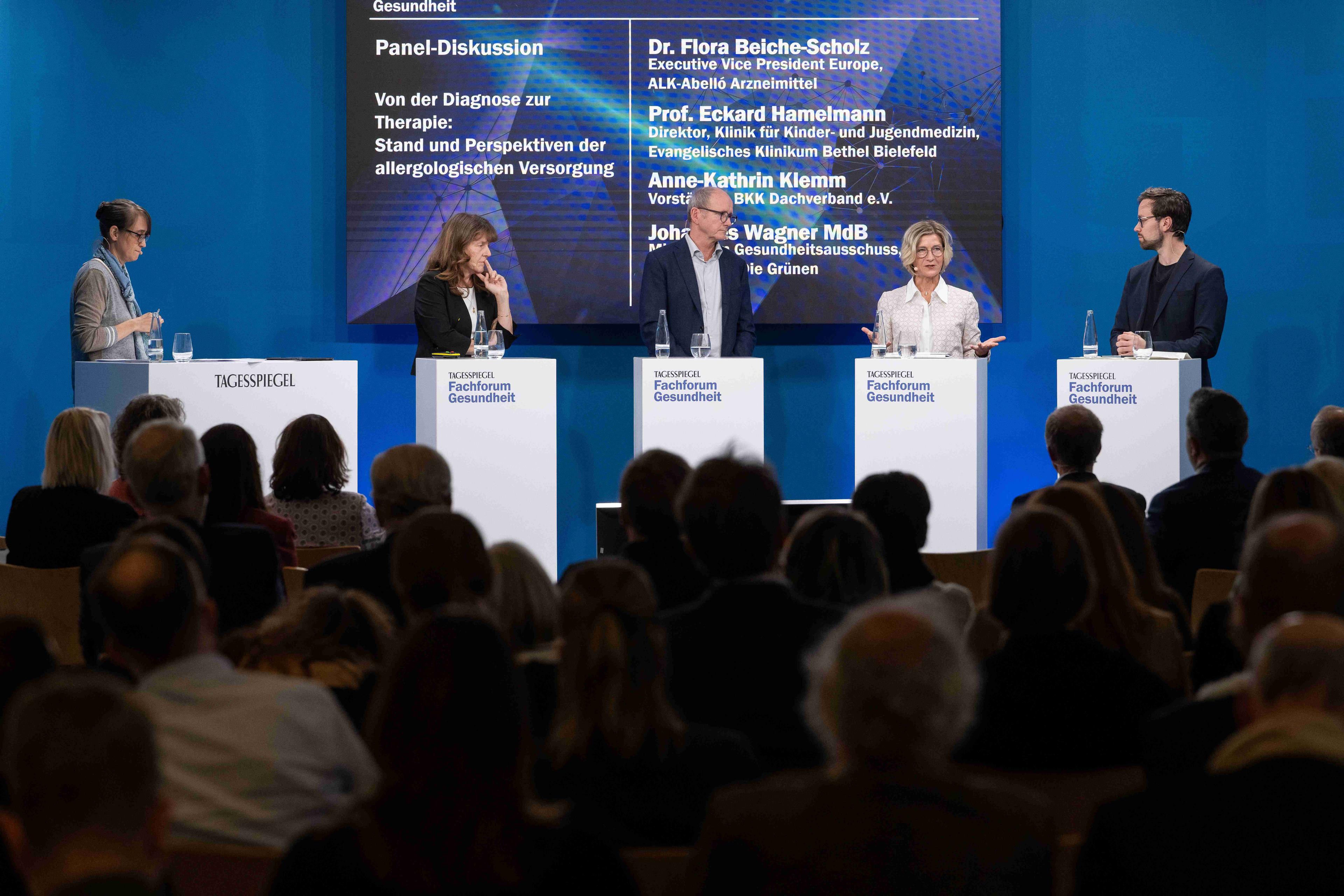 Fünf Personen diskutieren auf einer Bühne über die allergologische Versorgung; im Publikum sitzen Gäste.