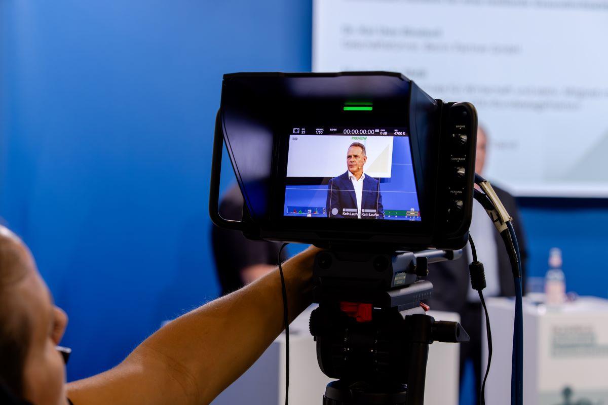 Kamera filmt einen Mann auf dem Podium.