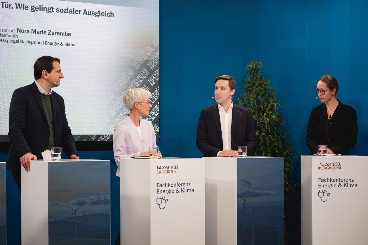 Podium mit vier Personen vor blauer Wand.