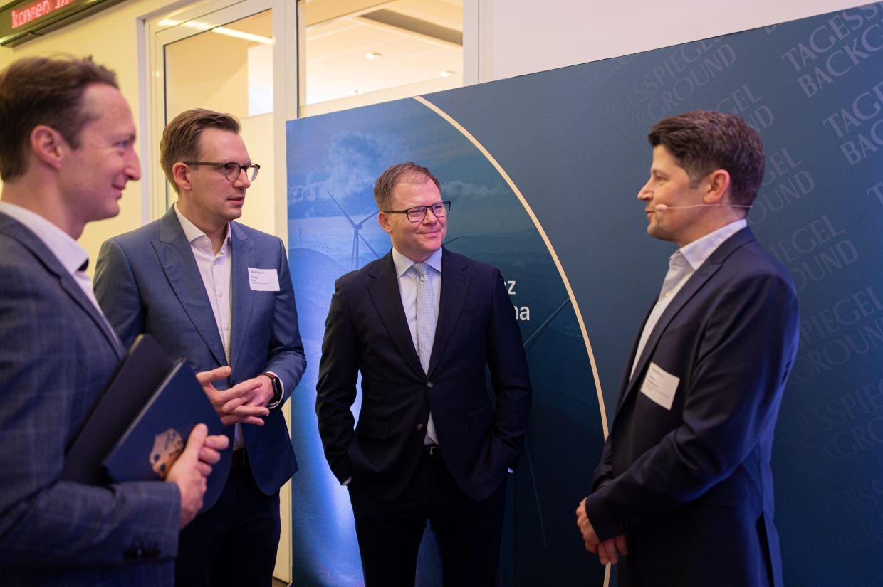 Gruppe im Foyer im Gespräch vor blauer Wand.