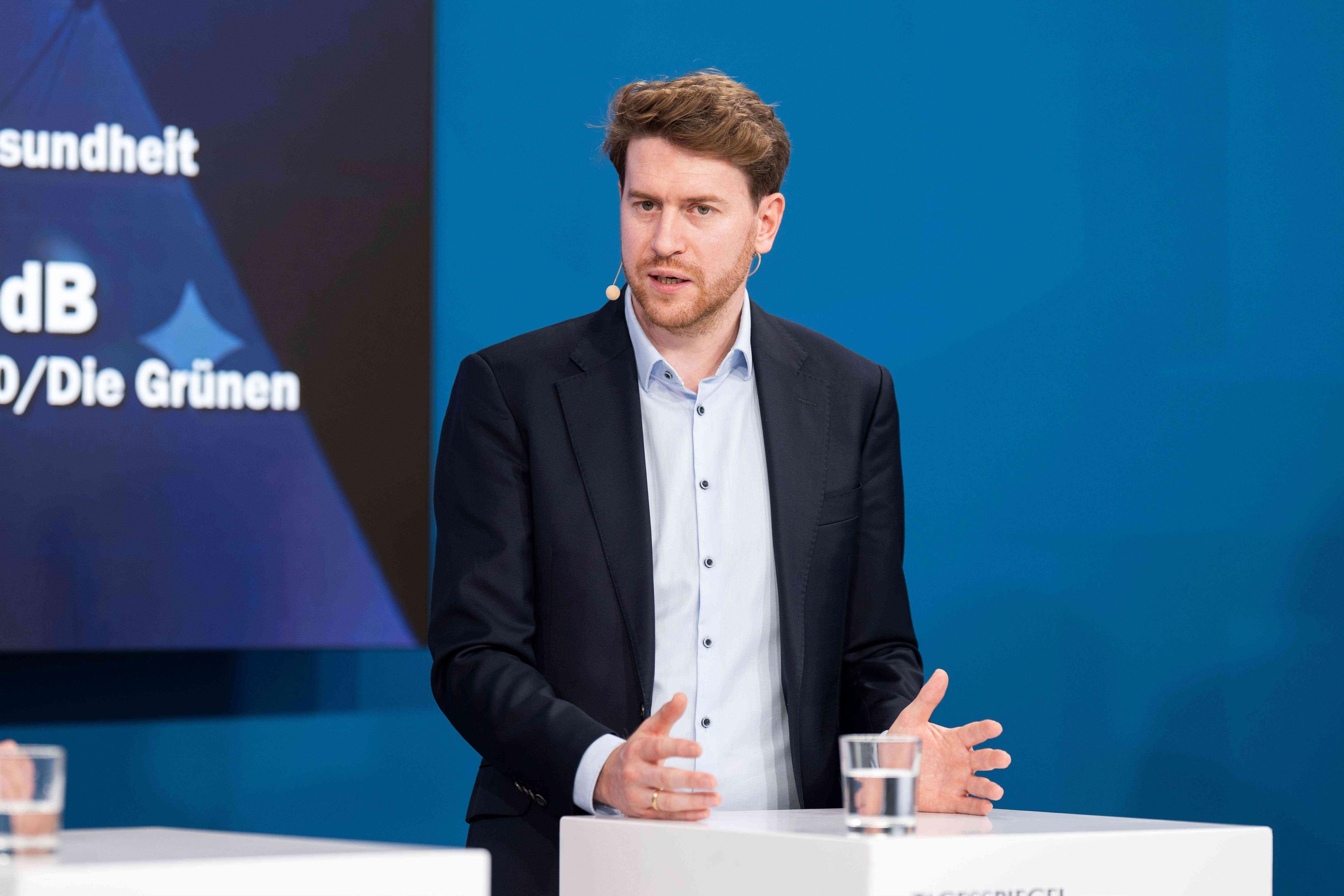 Ein Mann im Anzug steht auf der Bühne und spricht.